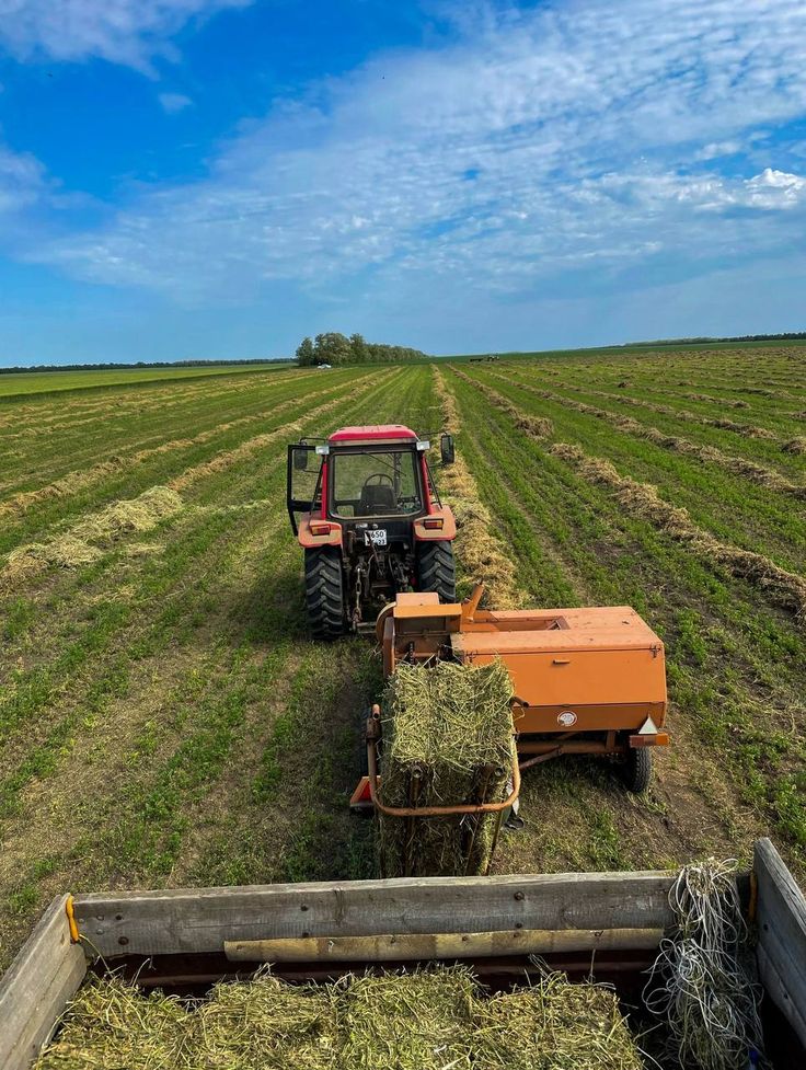Tractor baling hay across open farmland at BV Farms
